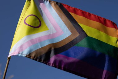Cinsiyetler arası çemberli Gurur Bayrağı açık mavi gökyüzüne karşı rüzgarda sallanıyor. LGBTQ gurur, kapsama ve insan haklarının sembolü.