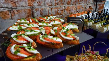 Domates, mozzarella, pesto ve otlu taze caprese bruschetta. Zarif bir yemek organizasyonu için güzel bir tepside hazırlanmış..