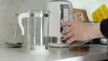 Sabah kahvesi rutini. Sıcak su elektrikli su ısıtıcısında kaynatılır, öğütülmüş kahve bir Fransız makinesine eklenir ve üzerine taze kahve demlemek için kaynar su dökülür. 4k 