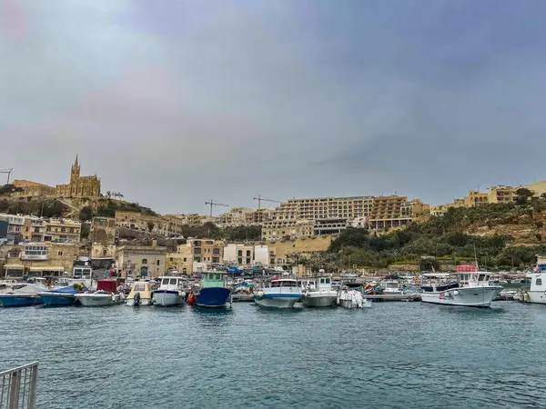 Huzurlu bir Malta limanında, yumuşak bir gökyüzünün altında, altın tepe binalarının altına kurulmuş bir yat dolusu tekne..