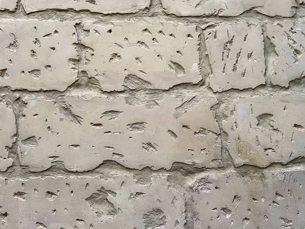 Görünür erozyon, çatlaklar ve keski izleriyle yaşlanmış kireçtaşı duvarına yakın plan. Malta 'daki tarihi binanın doğal dokulu arka planı.