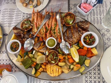Izgara karides, balık, sebze, sos ve limon dilimli zengin bir Akdeniz deniz ürünleri tabağının üst görüntüsü, Malta 'da bir açık hava restoranında servis ediliyor..