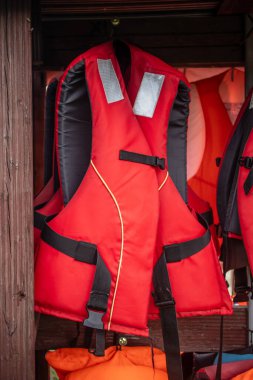 Parlak kırmızı bir can yeleği ahşap bir duvara asılır. Potansiyel olarak tehlikeli durumlarda güvenliği, hazırlığı ve korunmayı simgeler..