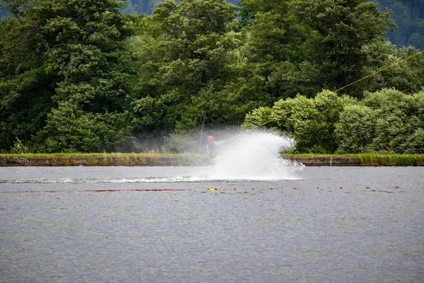 Su kayakçısı, yemyeşil ormanlarla çevrili bir gölde süzülürken büyük bir sıçrama yapar. Hareket, hız ve yaz eylemi kaydedildi.