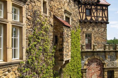 Güneşli bir günde Avrupa 'nın tarihi kale duvarına taş ustaları, sarmaşıklar, ahşap çerçeveler ve klasik pencerelerle yakın çekim.