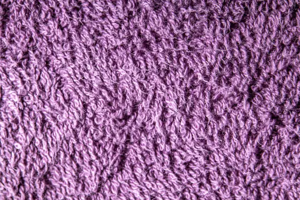 Mor bir kumaş yüzeyinin makro fotoğrafı ayrıntılı döngüler ve lifler gösteriyor. Yakın planda yumuşak desen ve canlı renk.