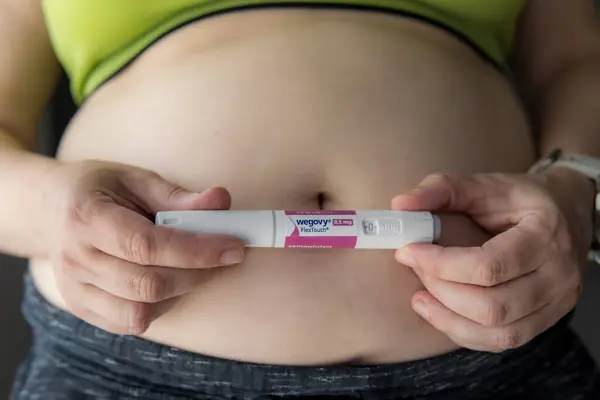 Yılan pençesi. Polonya. 29.07.2025 kadın karnının yanında Wegovy semaglutide enjeksiyon kalemi tutuyor. Kilo kaybı tedavisi ve obezite yönetimi kavramı.