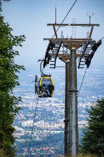 Sarı gondol Polonya 'da bir dağ halatının üzerinde, şehir ve doğal manzara panoramik manzaralı yolcuları taşıyordu..