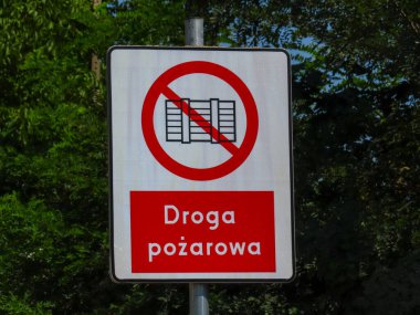 Trafik levhası, güneşli bir günde yeşil ağaçların arka planında park sembolü olmayan bir itfaiye şeridini gösteriyor..