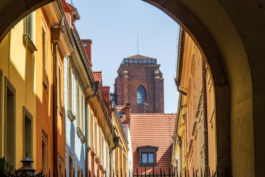 Renkli eski kasaba binaları ve Avrupa 'da bir kemer yolu tarafından çerçevelenmiş tarihi tuğla kule..