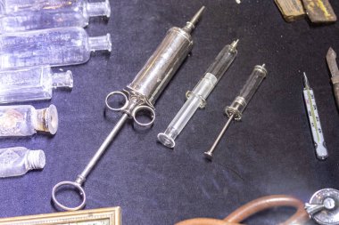 Eskimiş tıbbi şırınga seti ve karanlık bir arka planda cam termometre. Sağlık hizmetleri ve antika hastane ekipmanlarının tarihini sembolize eden tıbbi gereçler.