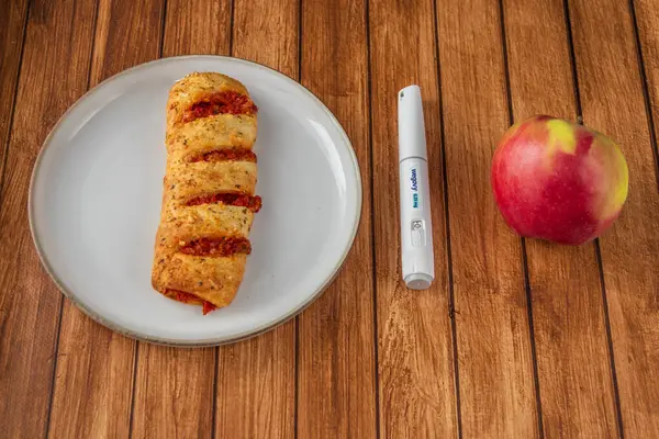 Sağlıklı ve sağlıksız yemek seçeneklerini gösteren kavramsal fotoğraf. Kilo verme iğnesi, elma ve ahşap bir arka planda hamur işi..