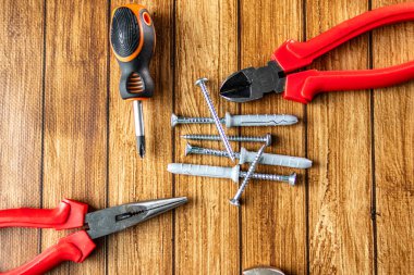 Tornavida, pense, tel kesici ve tahta arka planda metal vidalar gibi el aletleri. DIY ve inşaat konsepti. Üst görünüm.