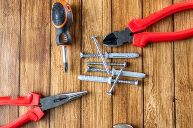 Tornavida, pense, tel kesiciler ve tahta yüzeydeki vidalar da dahil olmak üzere çeşitli el aletleri. Üst Manzara. Ev onarımı ve DIY konsepti.
