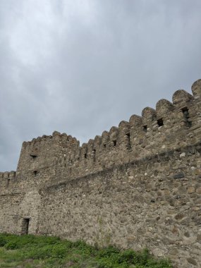 Bulutlu gökyüzüne karşı siperleri olan antik taş kale duvarı tarihi mimari ve ortaçağ savunma yapıları sergiliyor. Seyahat, tarih ve mimari temalar için mükemmel. 