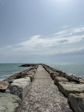 Yıpranmış eski bir taş iskeleye giden yol ufka doğru denize doğru uzanıyor.