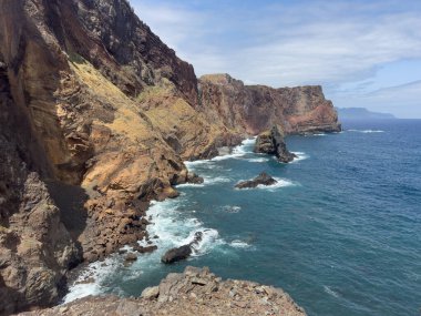 Resimli bir manzara var. Madeira Adası 'nın küçük körfezini gösteriyor. Yüksek kayalık kıyı şeridi de görülebilir durumda. Okyanus dalgaları da öyle. Seyahat kavramı