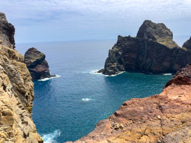 Madeira Adası ve yüksek, kayalık bir kıyı şeridi olan küçük bir koy. Okyanus dalgaları büyük kayalara çarpar ve dağlar bölgeyi sarar. Seyahat kavramı