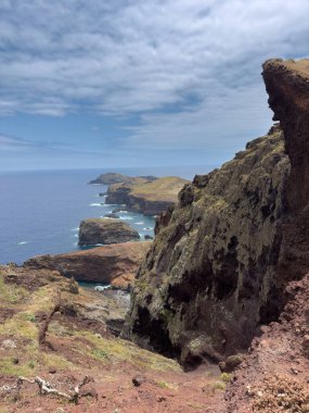 Portekiz 'deki Madeira Adası' nın ufukta uzanan kayalık kıyı şeridi manzarası. Beyaz sörflü deniz burnu, dağlar, büyük kayalar. Seyahat kavramı.