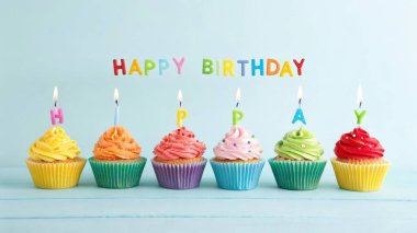 Mumlu renkli doğum günü kekleri ve doğum günü afişi.