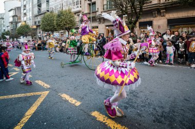Santiago de Compostela, İspanya, 4 Mart 2025: Renkli palyaço kostümlü oyuncular Santiago de Compostela, İspanya 'daki canlı karnaval geçidi sırasında dans ediyorlar