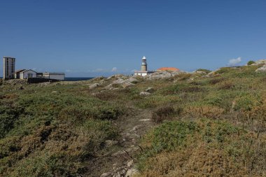 Açık mavi gökyüzünün altında Atlantik Okyanusu 'na bakan kayalık bir sahilde duran deniz feneri mantarı Galiçya' da manzaralı ve tarihi bir seyahat noktası sunar.