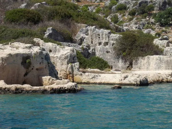 Berrak mavi suyu olan kayalık bir sahil şeridi, engebeli uçurumlar ve seyrek bitki örtüsü var. Sahne, doğa severler için ideal bir kıyı bölgesinin doğal güzelliğini yansıtıyor..