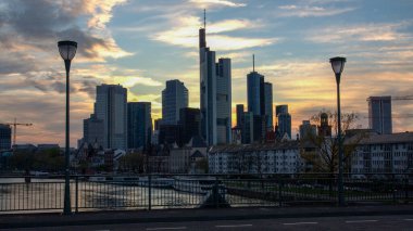 Frankfurt, Almanya 'nın göz kamaştırıcı bir gökdelenleri renkli bir günbatımına karşı sergiliyor. Sahne, nehirdeki yansımaları ve şehir mimarisini içeriyor..
