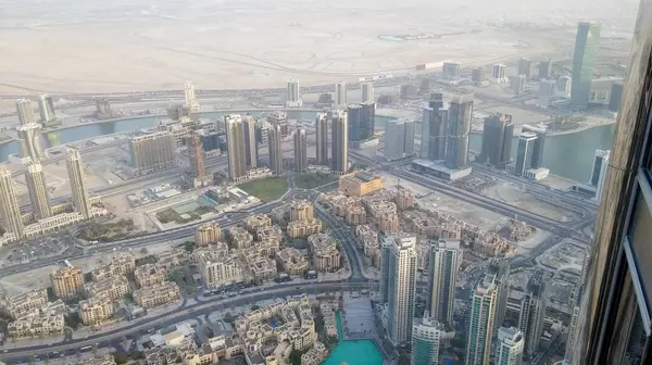 Yüksek binaların, dolambaçlı yolların ve bir nehrin yer aldığı modern bir şehir manzarası. Manzara, sisli bir gökyüzü ile kentsel gelişim ve doğal arazi karışımını gösteriyor..