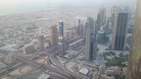 Gökdelenleri, otoyolları ve kıyı şeridi olan modern bir şehrin havadan görünüşü. Ufuk çizgisinde, kentsel gelişim ve altyapı sergilenen mimari tarzların bir karışımı yer alıyor..