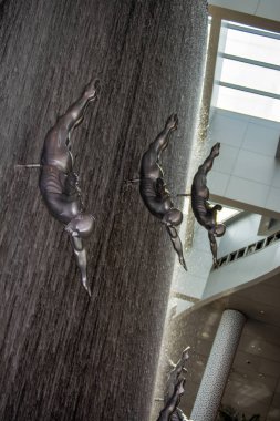 Havada dalgıçların metalik heykellerini içeren çarpıcı bir kapalı şelale dinamik bir görsel etki yaratıyor. Geniş pencerelerden süzülen doğal ışıkla modern ve ferah bir ortam..