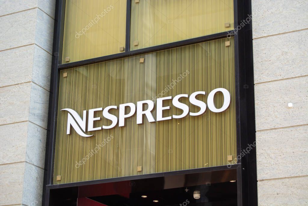 A close-up view of a Nespresso store sign, featuring the brand name in bold white letters against a backdrop of textured golden glass.