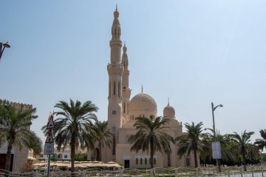 Uzun minareleri ve büyük bir kubbesi olan, palmiye ağaçları ve açık mavi gökyüzü ile çevrili güzel bir cami. Mimaride karmaşık tasarımlar ve açık renkli bir cephe yer alıyor..