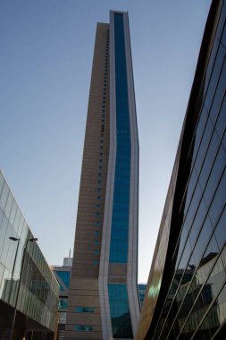 Eşsiz bir tasarımı olan, cam ve beton kombinasyonlu, uzun, modern bir gökdelen. Bina, çağdaş bir kentsel ortamı yansıtan diğer yapılarla çevrilidir..