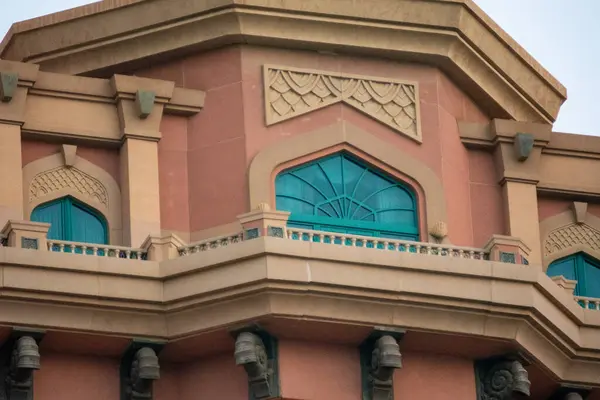 Süslü pencereler ve sıcak renk paletinde dekoratif elementler bulunan bir binanın mimari ayrıntıları.