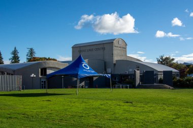 Büyük Göl Merkezi 'nin önündeki yeşil çimlere kurulmuş büyük mavi bir çadır. Çatı kıvrımlı ve arka planda açık mavi gökyüzü olan modern bir bina..