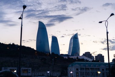 Bakü, Azerbaycan - 30 Temmuz 2023: Dramatik günbatımında şehrin gökyüzüne hakim olan Alev Kuleleri binaları