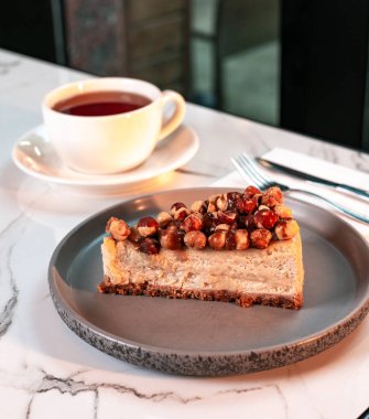 Fındıklı Karamelli Cheesecake Gri Tabakta dilimlenmiş Mermer Masada Çay