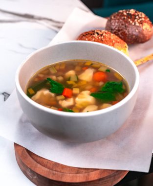 Havuçlu sebze çorbası, karnabahar ve mermer masadaki ekmekle birlikte yeşillikler.