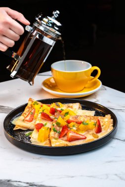 Meyveli krep, limon sosu ve böğürtlenli, Han tarafından sıcak çayla servis ediliyor.