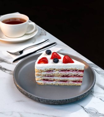 Kremalı ve taze meyveli vanilyalı pasta Beyaz Kupa 'da sıcak çayla servis edilir.