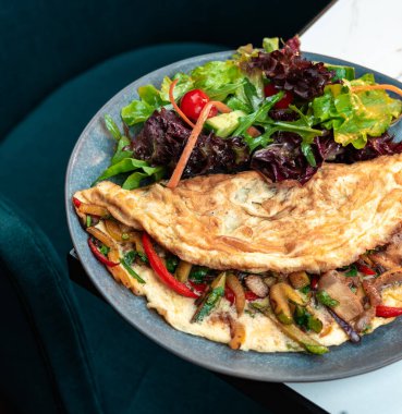 Doldurulmuş sebzeli omlet ve karışık salata. Parlak kiraz domatesleri ve renkli biberler. Sağlıklı menüler, kahvaltı, yemek blogları için mükemmel..