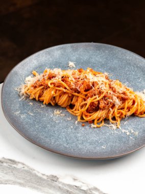 Klasik spagetti bolonez, parmesan peyniri ve mavi tabakta fesleğen. Restoran reklamları için geleneksel İtalyan makarna yemeği.