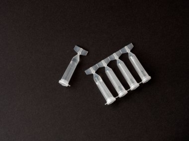 Tek kullanımlık göz damlaları koyu arka planda izole edilmiş. Göz damlası paketi tek kullanımlık konteynırlar. Göz bakımı konsepti. kuru göz tedavisi. Üst manzara, düz uzanma