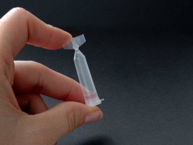 El ele tutuşan tek kullanımlık göz damlaları koyu arka planda. Göz damlası paketi tek kullanımlık konteynırlar. Göz bakımı konsepti. kuru göz tedavisi. 