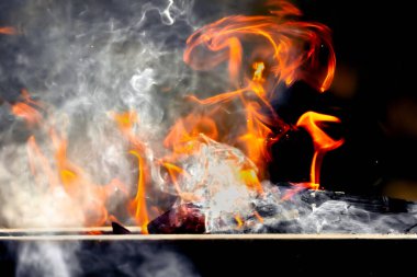 Alevlerin arka planı. Yangın arka planı yanıyor. Ateş alevi. Yangın arka planı. Ateş dokusu. Alevler. Karanlık odunların üzerinde beyaz duman.