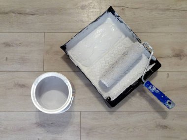 Mavi saplı, gri boyalı ve doğal ahşap arka planda gri boya kutusuyla en üstteki boya rulosu.