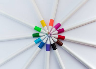 Beyaz fininerler beyaz arka planda, dairesel düzenleme. Çok renkli kalemler. yaratıcılık, eğitim, sanatsal ifade kavramı