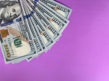 Mor bir yüzeye yayılmış yüz dolarlık banknotların yakın çekim hayranı. Finans, para, zenginlik ve finansal planlamanın sembolü. İş, ekonomi ve yatırım görselleri için kullanışlı