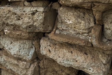 Eski, dokulu tuğlaları olan taştan bir duvara yakın plan. Yüzeyde doğal aşınma ve çatlaklar, tasarım projelerinde grunge arkaplan veya yapı dokusu olarak kullanılmak için idealdir. Yüksek kalite